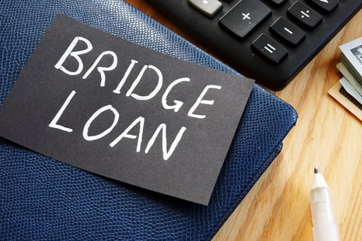 bridge loan written on card on top of binder next to calculator and money stack