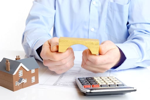 man holding wooden bridge model next to calculator and paperwork