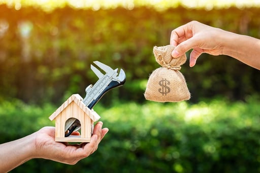 man hand holding a wooden home with tools and woman holding money bag