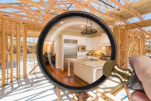 Hand Holding Magnifying Glass Revealing Finished Kitchen Over Construction Framing