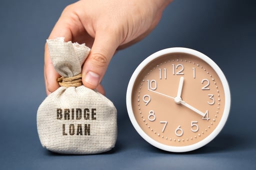 Money bag with Bridge Loan text printed on it next to clock