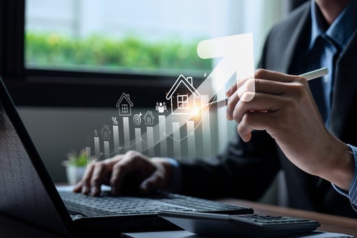 Broker using laptop and holding pen with chart showing real estate growth overlayed
