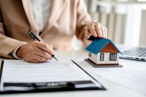Real estate broker signing sales agreement with model of a home on the table