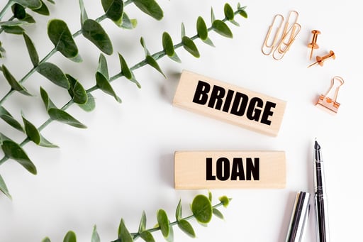 Bridge loan concept written on wooden blocks, with office stationery and green plant on white background