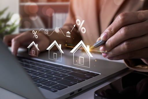 Broker using laptop and holding pen with graph and images of homes growing in front of them