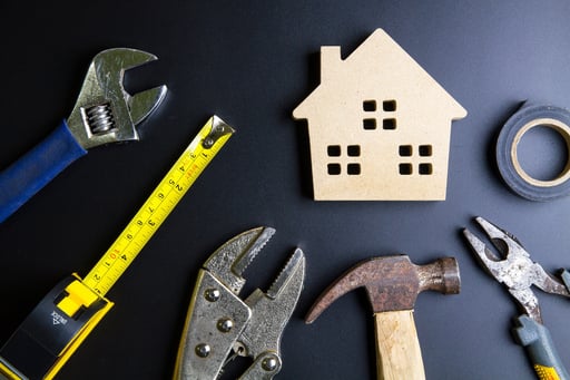 Wooden house model and construction tools on black background