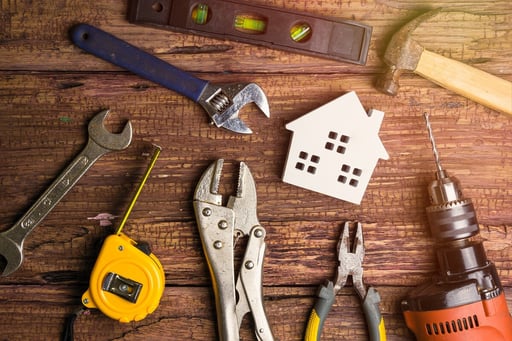 white toy house and construction tools on wooden background